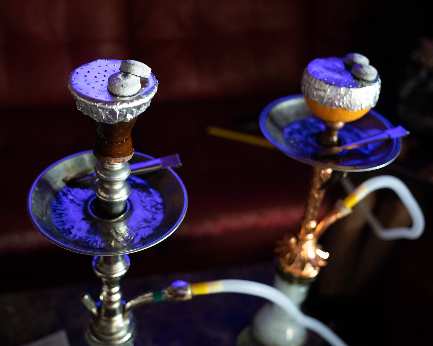 Two hookah pipes on a table in a dimly lit indoor lounge.