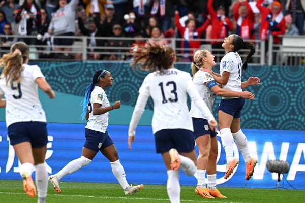 Sophia Smith, at right, jumps into the air in the arms of a team as other U.S. players run to join the celebration.